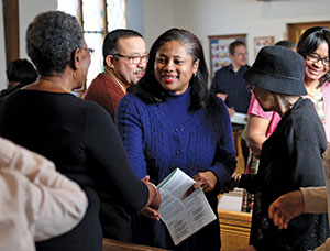 KRISTA KENNELL Jennifer Pierre (in blue) shakes hands during Sunday worship at Our Saviour, which implemented a welcoming ministry that saved it from being closed.