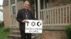 Pastor Fred Schenker holds a sign with religious symbols in front of his home.