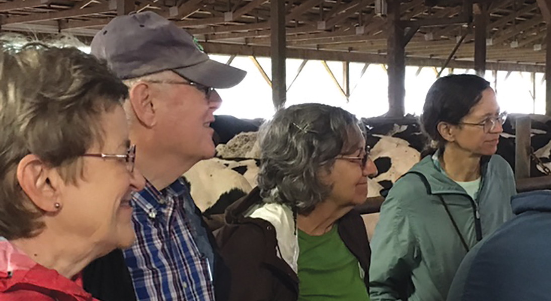 Four people visit a dairy farm.
