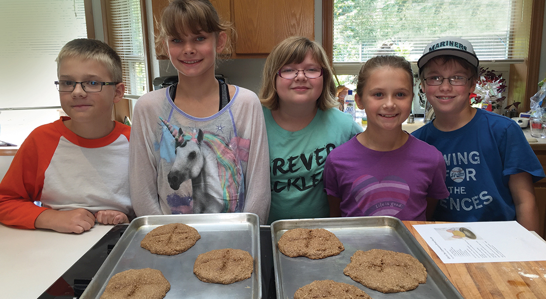 3 children display two pans of fresh communion bread