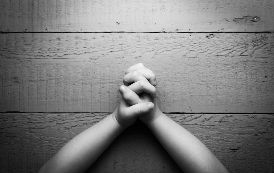 Child's hands folded together in prayer