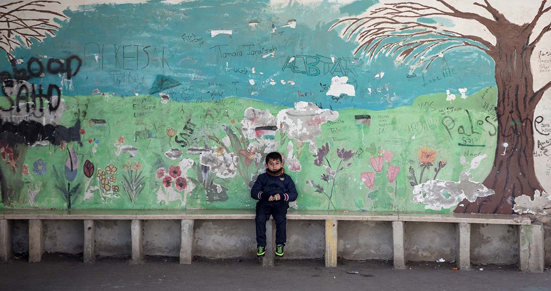 A boy sits alone on the worn and graffittied playground at the old Evangelical Lutheran School of Hope in Ramallah.