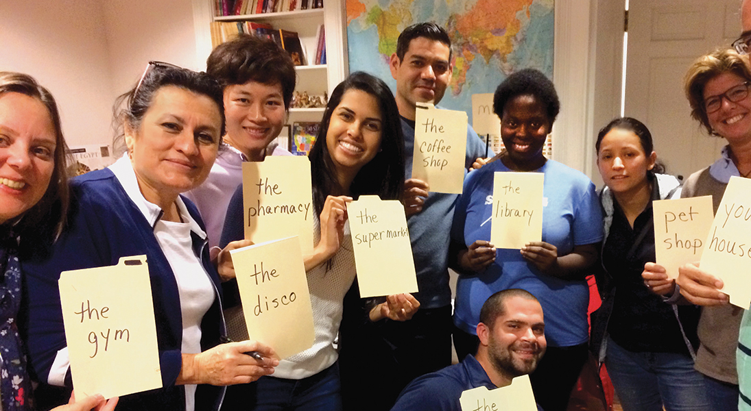 Students in an English as a second langage class hold up cards with the English words for places.