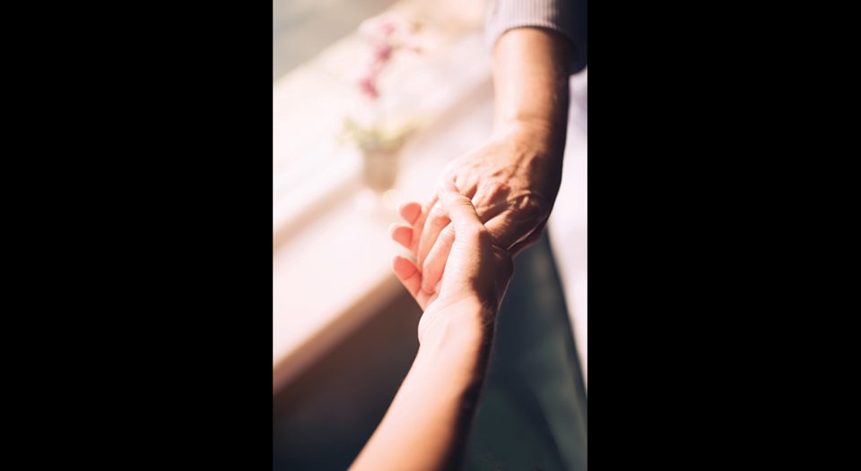 A young hand holds an older hand