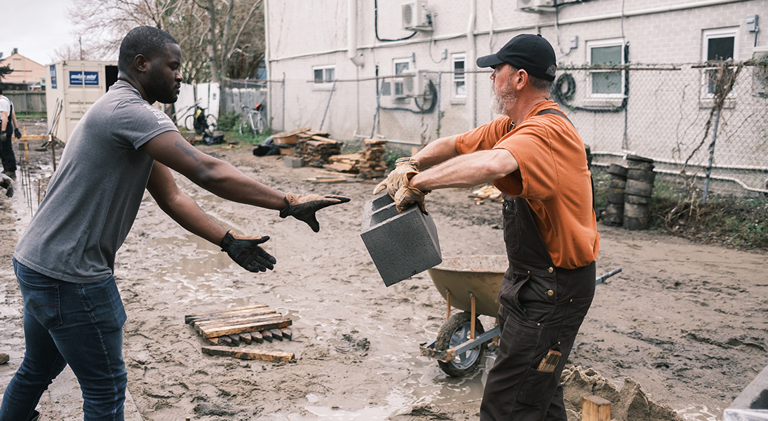 A Tulane professor and student move concrete blocks for a housing foundation