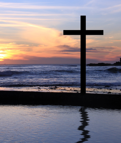 a cross on the beach at sunset
