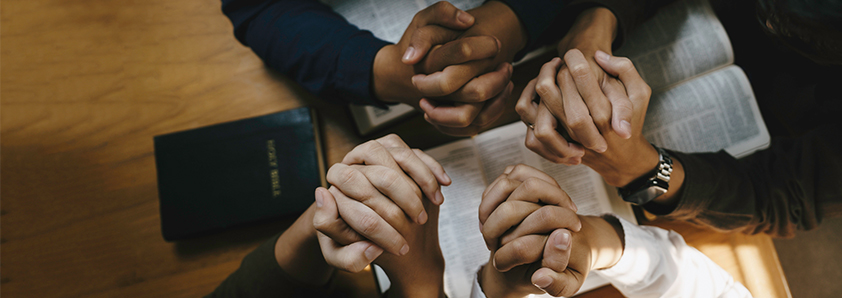Many hands clasped in prayer