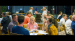 A crowd of people sitting and talking at tables